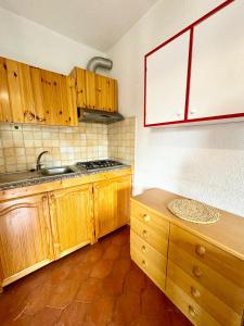 a kitchen with wooden cabinets and a counter top at Bilocale al Villaggio degli ulivi SAN TEODORO in San Teodoro