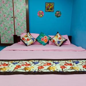 um quarto com uma cama com lençóis e almofadas cor-de-rosa em Blue Waves HomeStay em Pondicherry