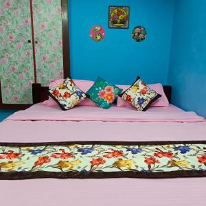 a bedroom with a bed with pink sheets and pillows at Blue Waves HomeStay in Pondicherry