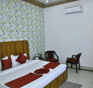 Hotel Shiwalik Enclave في Baddi: غرفة نوم بسرير كبير مع كرسيين
