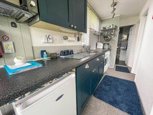 a kitchen with blue cabinets and a black counter top at Lovely 4 Berth Chalet In The Coastal Village Of Heacham, Ref 92018cs in Heacham