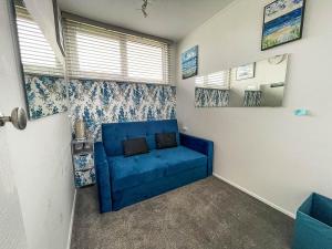 a blue couch sitting in a room with windows at Lovely 4 Berth Chalet In The Coastal Village Of Heacham, Ref 92018cs in Heacham