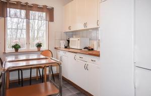 eine Küche mit weißen Schränken, einem Tisch und einer Mikrowelle in der Unterkunft 3 Bedroom Lovely Home In Borrby in Borrby