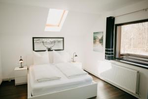a white bedroom with a bed and a window at CABANA BERNER stațiunea Mogoșa in Baia-Sprie
