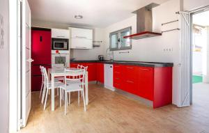 a kitchen with red cabinets and a table with chairs at 3 Bedroom Amazing Home In El Mojón in El Mojón