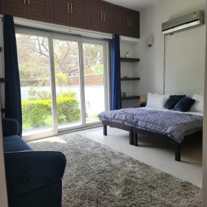 een slaapkamer met een bed en een groot raam bij Luminary Dynasty House in Gurgaon