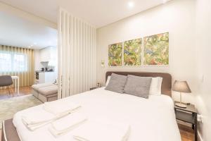 a bedroom with a white bed and a living room at Braga Center Apartments - Eça de Queirós in Braga