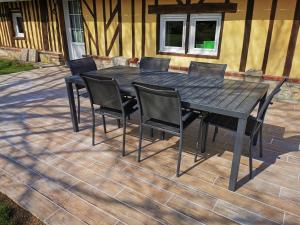 - une table et des chaises noires sur la terrasse dans l'établissement La Bergerie, à Cambremer