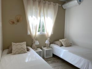two beds in a room with a window at LA VILLA ALBA in Les Issambres