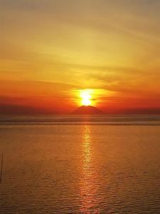 um pôr-do-sol sobre o oceano com uma montanha ao fundo em BLOOM em Tropea