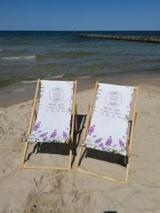 two beach chairs sitting on the sand on the beach at Lawendowy Zakątek in Sianozety