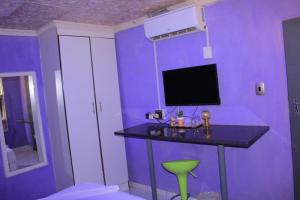 a purple room with a table with a tv on it at Magagula's Guest House and Accomodation in Burgersfort