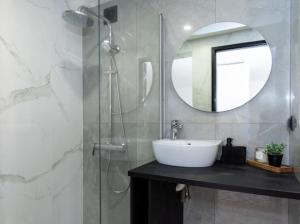 ein Bad mit einem Waschbecken und einer Dusche mit einem Spiegel in der Unterkunft Cozy little home, Mai 17 in Pärnu