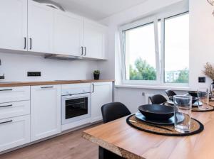 een keuken met witte kasten en een houten tafel bij Cozy little home, Mai 17 in Pärnu