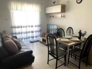 ein Wohnzimmer mit einem Tisch, Stühlen und einem Sofa in der Unterkunft Quiet, Cosy Mellieha Apartment In Ghadira Bay in Mellieħa