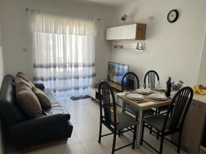 ein Wohnzimmer mit einem Tisch und einem Sofa in der Unterkunft Quiet, Cosy Mellieha Apartment In Ghadira Bay in Mellieħa
