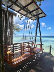 two benches hanging from a porch overlooking the ocean at White Bada Guesthouse in Siquijor