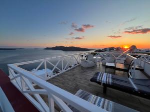 a balcony with a view of the ocean at sunset at Maryloujohn Villas Oia in Oia