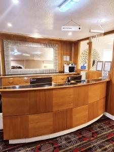 a large kitchen with wooden cabinets and a large mirror at Barons Court Hotel Walsall in Walsall