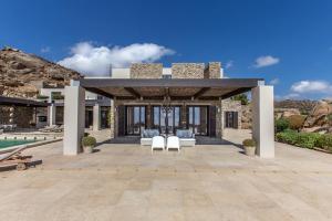 a pavilion with two white chairs on a patio at Endorikles Villa in Super Paradise Beach