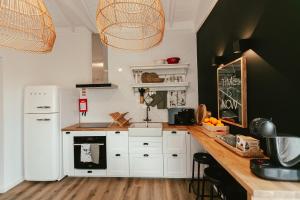 a kitchen with white cabinets and a white refrigerator at Aires Hostel in São Roque do Pico
