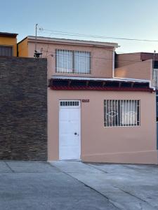 a pink building with a white door and a brick wall at Casa Central, Amplia y Cómoda in Antofagasta