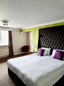 a bedroom with a large bed with purple pillows at Barons Court Hotel Walsall in Walsall