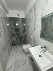 bagno bianco con lavandino e servizi igienici di Hotel Kaloshi a Tirana