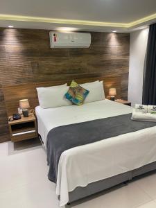 a bedroom with a large white bed and wooden wall at Hotel Pousada Casacolina in Búzios