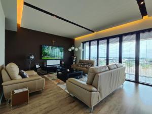 a living room with couches and a flat screen tv at Bright Cozy Waterfront in Sibu