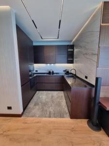 a kitchen with brown cabinets and a sink in it at Premium apartment in Porta Batumi Tower in Batumi