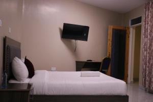 a bedroom with a bed and a tv on the wall at Motel Clavina in Gilgil