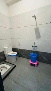 a bathroom with a toilet and a blue bucket at Hotel Raj Krishanam in Khātu
