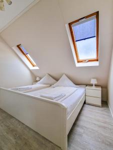 a white bedroom with a bed with a window at Dörte in Greetsiel