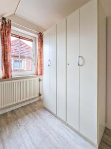 an empty room with white cabinets and a window at Dörte in Greetsiel