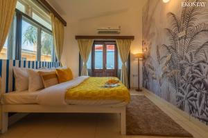 a bedroom with a bed with yellow sheets and a mural at EKOSTAY - Utopian Villa with Jacuzzi in Candolim