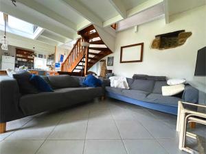 a living room with two couches and a staircase at Maison Les Agapanthes. in Lanmodez