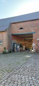 a large brick building with a stone courtyard at Glamping Hoeve Thenaers in Gingelom