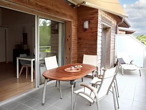 a wooden table and white chairs on a patio at Appartement charmant à Porto-Vecchio avec piscine partagée, 43 m² in Porto-Vecchio