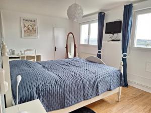 a bedroom with a bed with a blue comforter at La fleur du soleil in Trouville-sur-Mer