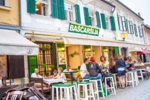 Baščaršija Apartments & Rooms في ماريبور: مجموعة من الناس يجلسون على الطاولات خارج المطعم