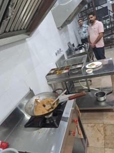Hotel Shiwalik Enclave في Baddi: رجلين واقفين في مطبخ مع wok