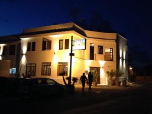twee mensen die 's nachts voor een gebouw lopen bij Hotel Il Pirata in Cinisi