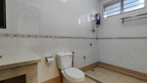 a white bathroom with a toilet and a shower at Sibu T1 Homestay, 4 Bedrooms in Sibu +26 photos