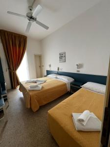 Cette chambre comprend deux lits et un ventilateur de plafond. dans l'établissement Hotel Till, à Rimini