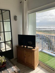 ein Wohnzimmer mit einem Flachbild-TV und einem Balkon in der Unterkunft Appartement face mer PROCHE PLAGE in Les Sables-dʼOlonne