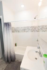 a white bathroom with a tub and a sink at Mins to NYC - Stylish 3 Bedroom Haven in Jersey City