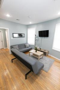 a living room with a couch and a tv at Mins to NYC - Stylish 3 Bedroom Haven in Jersey City