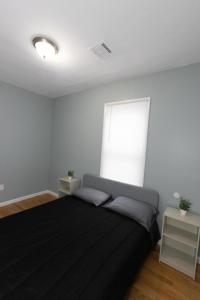 a bedroom with a black bed and a window at Mins to NYC - Stylish 3 Bedroom Haven in Jersey City