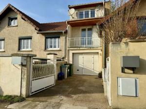 a house with a gate and a garage at La petite Maison chaleureuse in Jouars-Pontchartrain